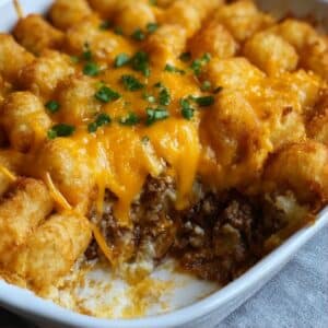 Close-up of cheesy tater tot casserole with crispy golden tater tots layered over seasoned ground beef.