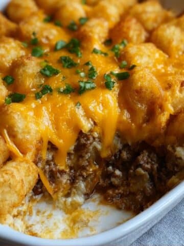 Close-up of cheesy tater tot casserole with crispy golden tater tots layered over seasoned ground beef.