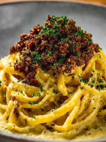 Creamy parmesan beef linguine topped with savory minced beef, silky garlic butter sauce, and fresh parsley, served in a bowl with rich golden noodles coated in cheese sauce.