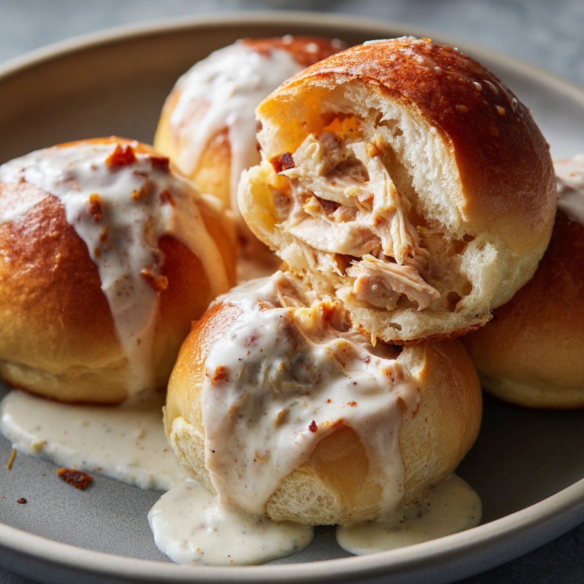Buffalo chicken sweet rolls with shredded chicken and cheddar cheese filling, topped with white glaze and red pepper flakes, shown with one roll cut open to reveal the spicy chicken interior