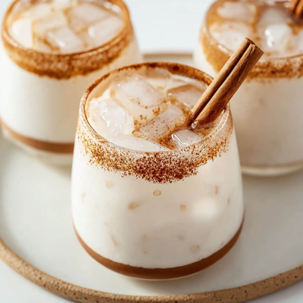 Easy homemade horchata served over ice with cinnamon sugar rim and cinnamon sticks