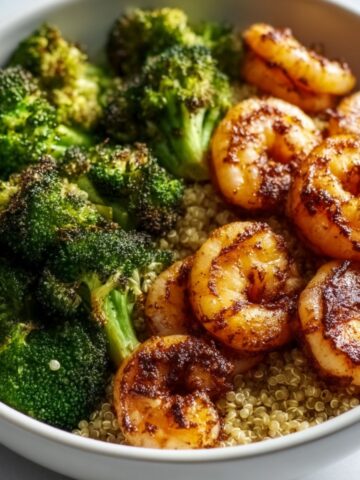 Easy shrimp quinoa bowl with seasoned pan-seared shrimp, fluffy quinoa, and roasted broccoli florets served in a white bowl.