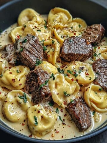 Garlic steak tortellini served in a creamy Parmesan sauce with tender steak bites, cheese-filled tortellini, herbs, and red pepper flakes