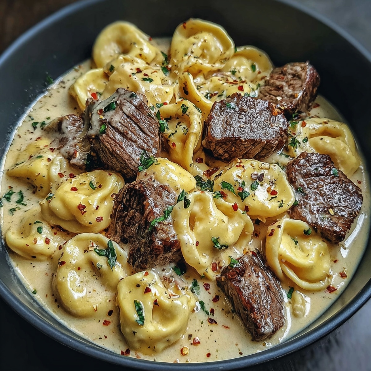 Garlic steak tortellini served in a creamy Parmesan sauce with tender steak bites, cheese-filled tortellini, herbs, and red pepper flakes