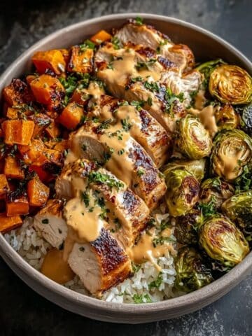 Maple Dijon chicken bowl with sliced roasted chicken, sweet potatoes, Brussels sprouts, and rice drizzled with creamy maple Dijon sauce