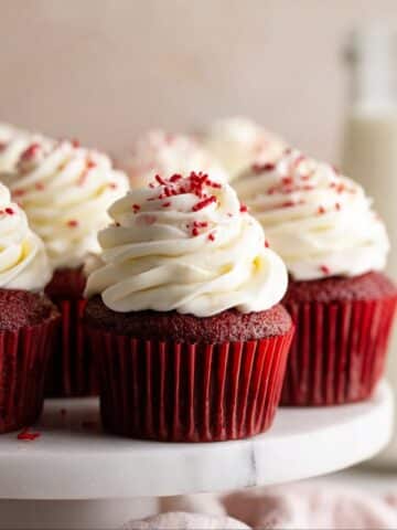 Red velvet cupcakes topped with cream cheese frosting and red sprinkles