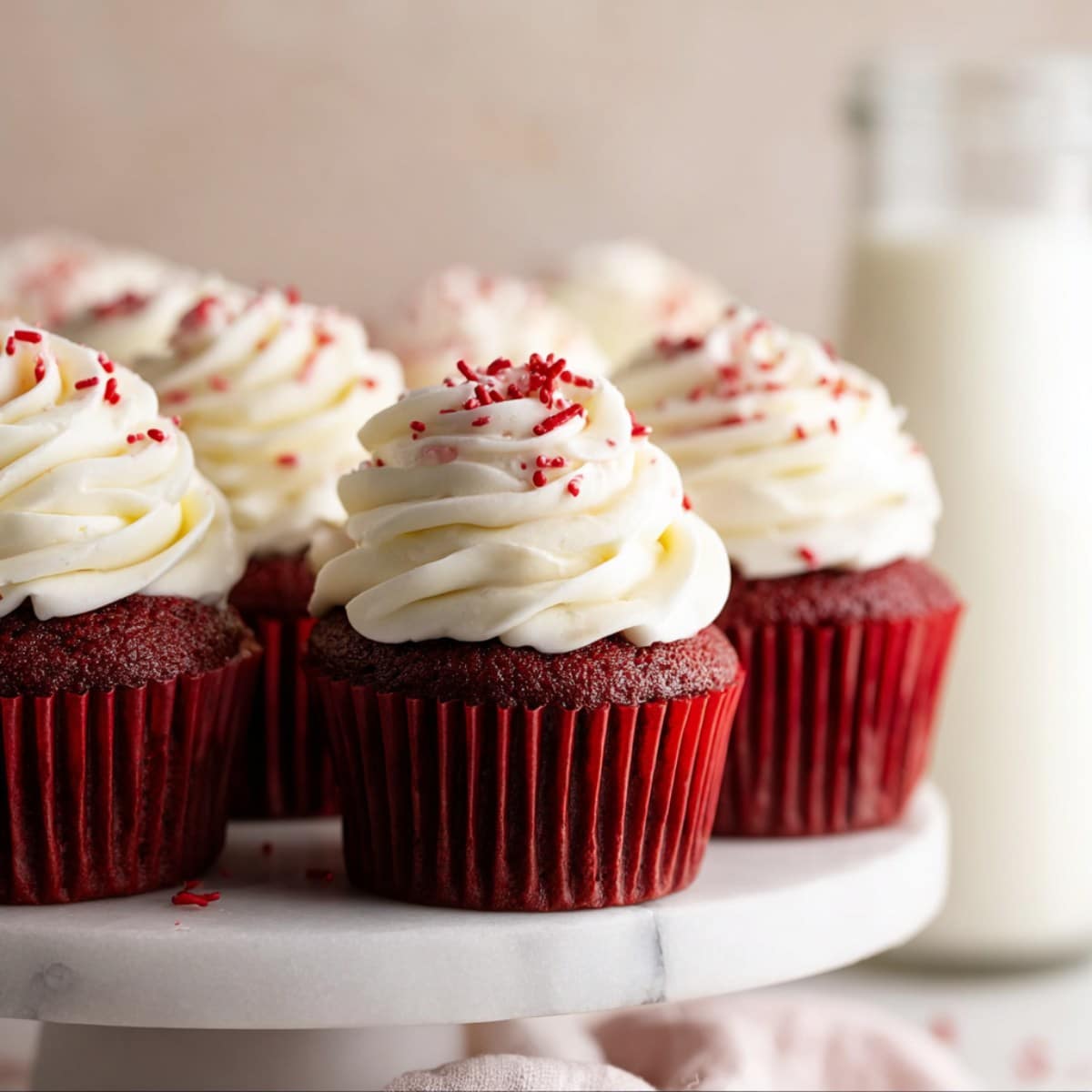 Red velvet cupcakes topped with cream cheese frosting and red sprinkles
