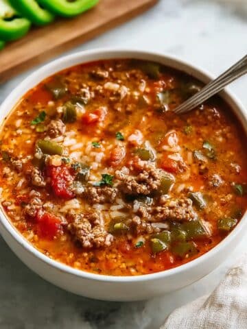 Stuffed pepper soup made with ground beef, tender rice, diced tomatoes, and green bell peppers in a hearty, seasoned tomato broth, served warm in a white bowl.