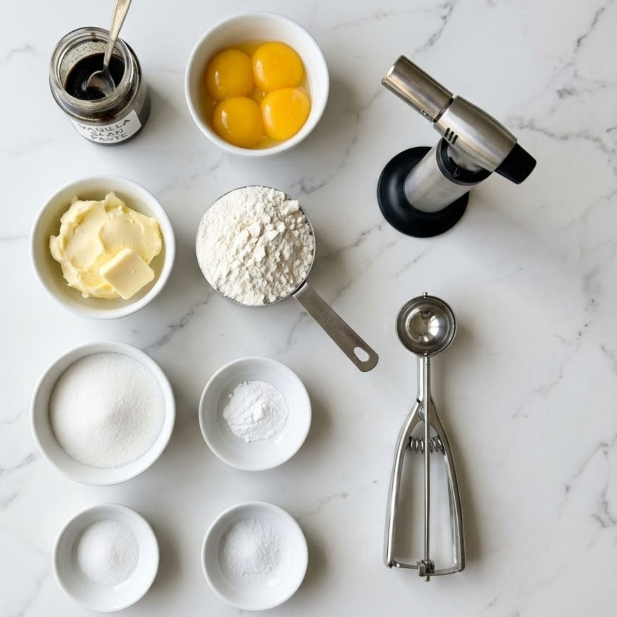 An organized overhead flat lay view of raw ingredients for Crème Brûlée Cookies, including vanilla paste, egg yolks, butter, and flour, arranged in neat bowls on a white marble kitchen counter with natural light.