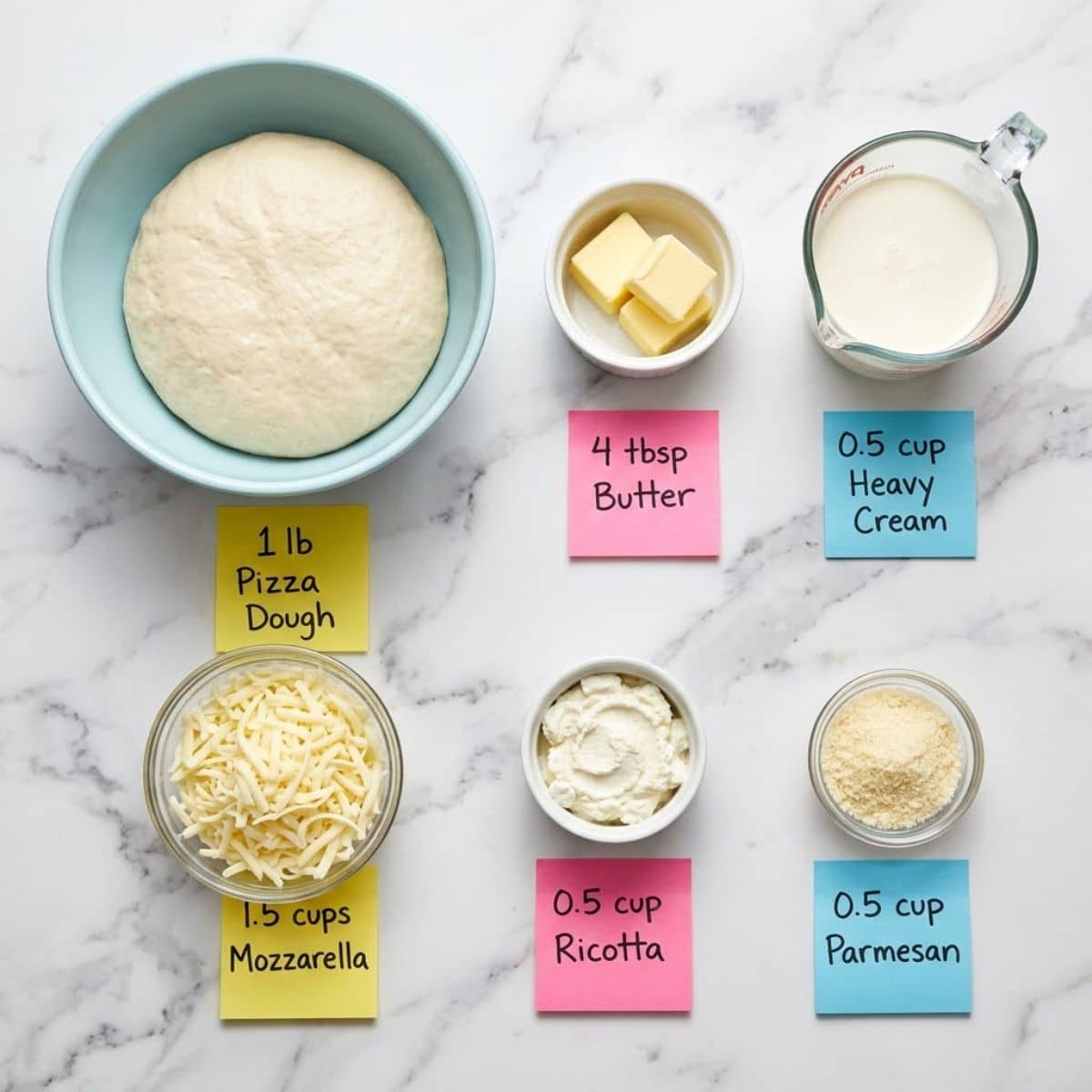 Overhead flat lay of raw White Sauce Pizza ingredients with labeled sticky notes on marble.