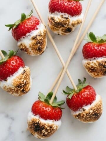 An overhead top-down view of Toasted Marshmallow Strawberries placed on white marble kitchen counter.