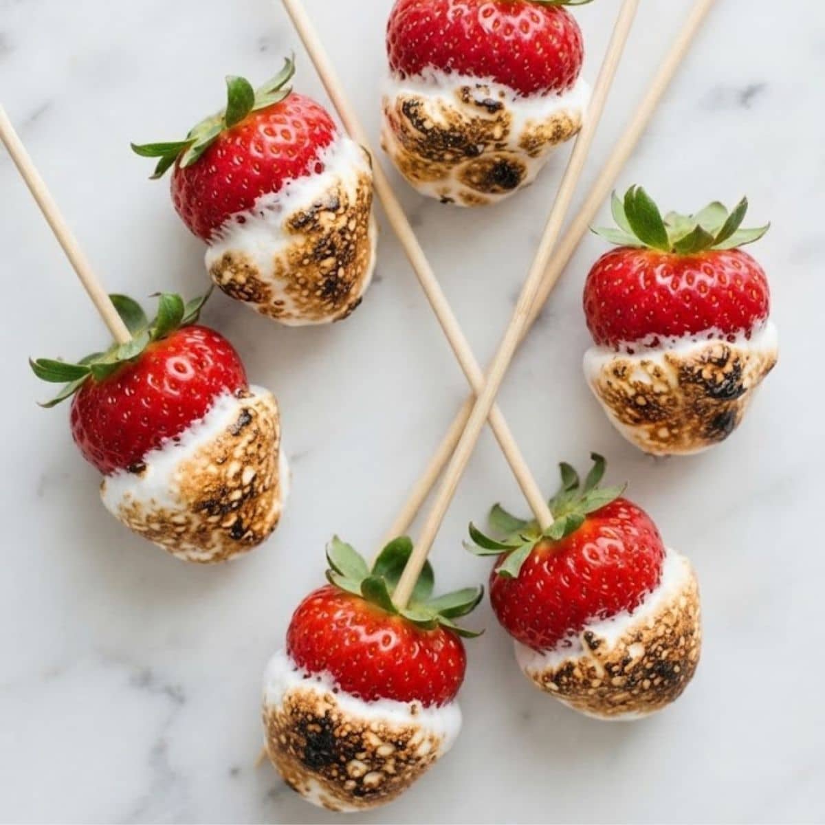 An overhead top-down view of Toasted Marshmallow Strawberries placed on white marble kitchen counter.